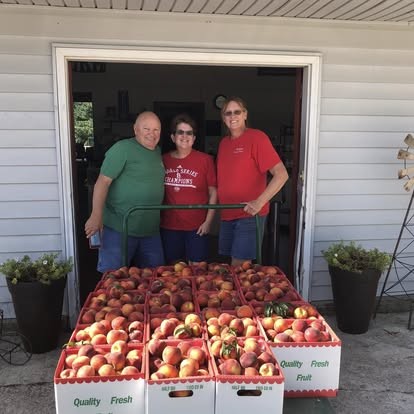 Debbie with customers and a cart full of peaches