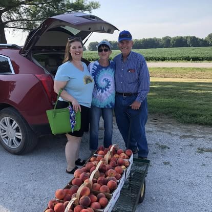 Happy customers leaving the stand with a cart of peaches